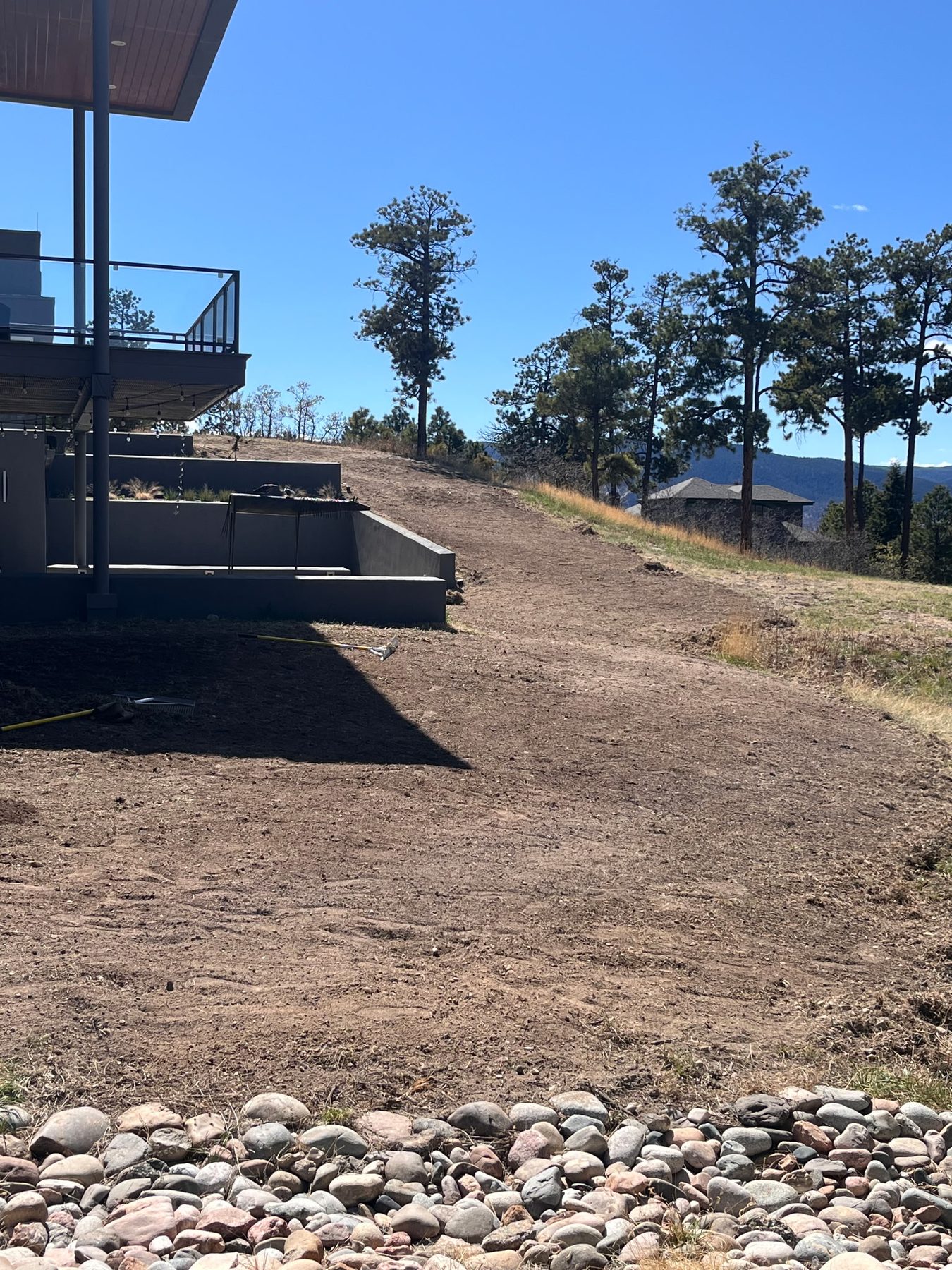 Raked and leveled soil prep running up to a finished patio and river rock border