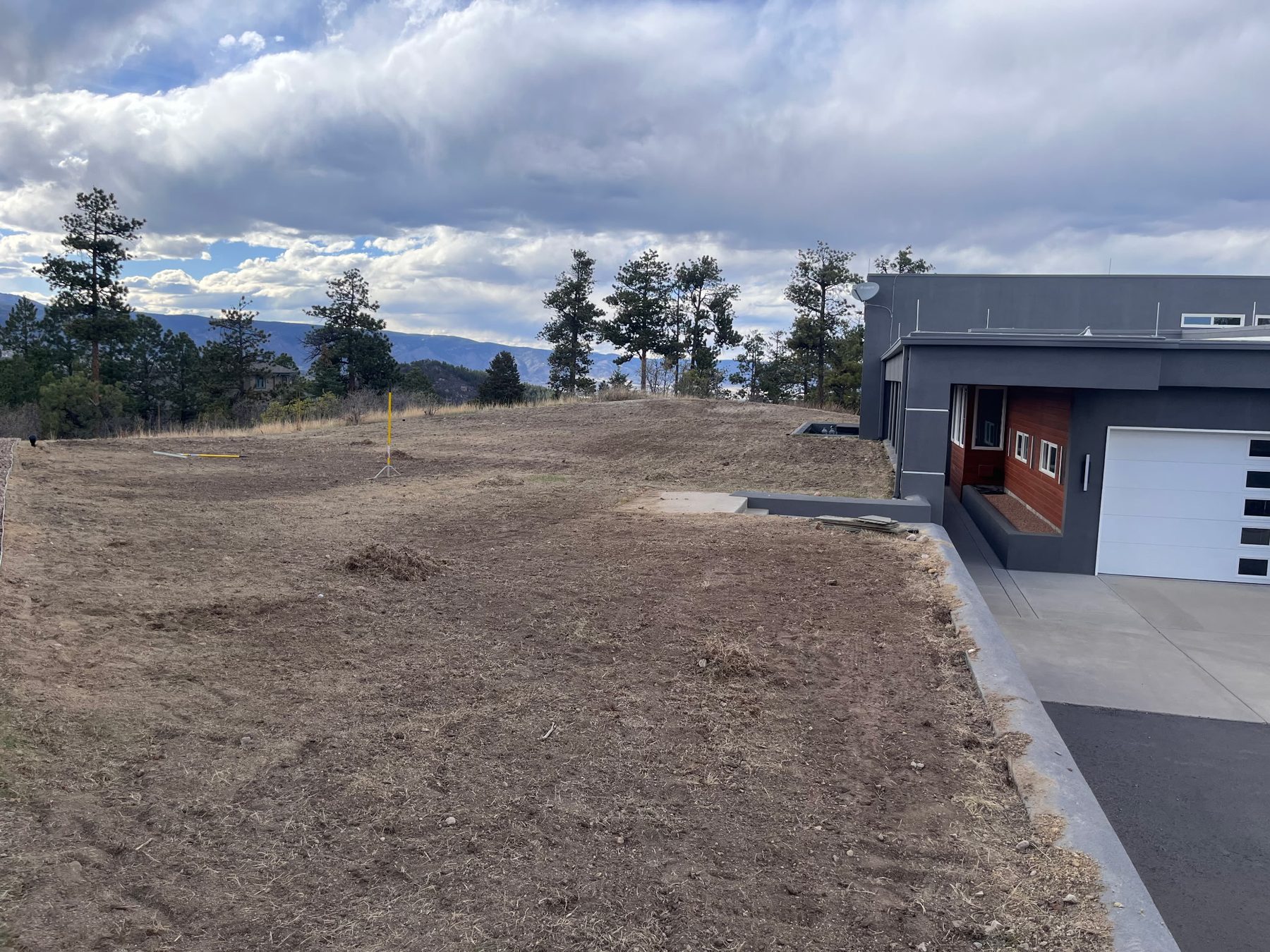 Graded and prepped soil ready for sod alongside a modern hillside home.