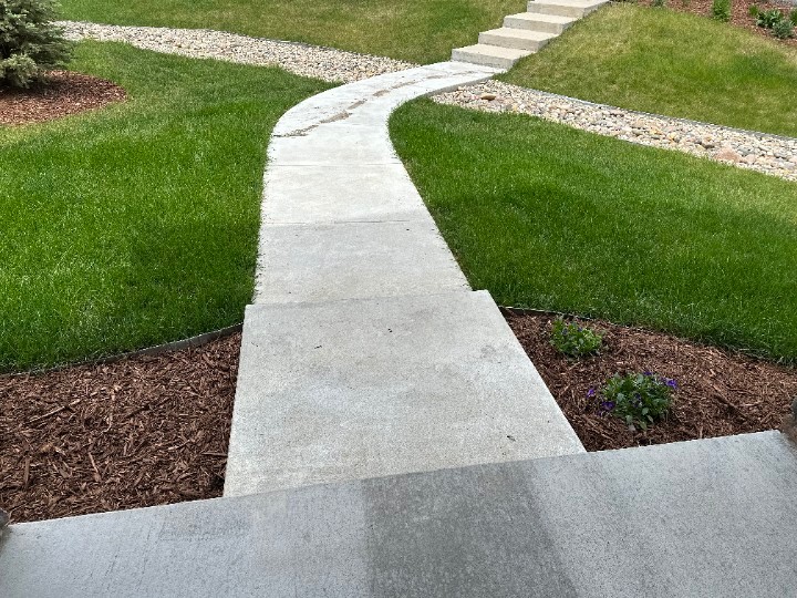Curved concrete walkway running through a green lawn